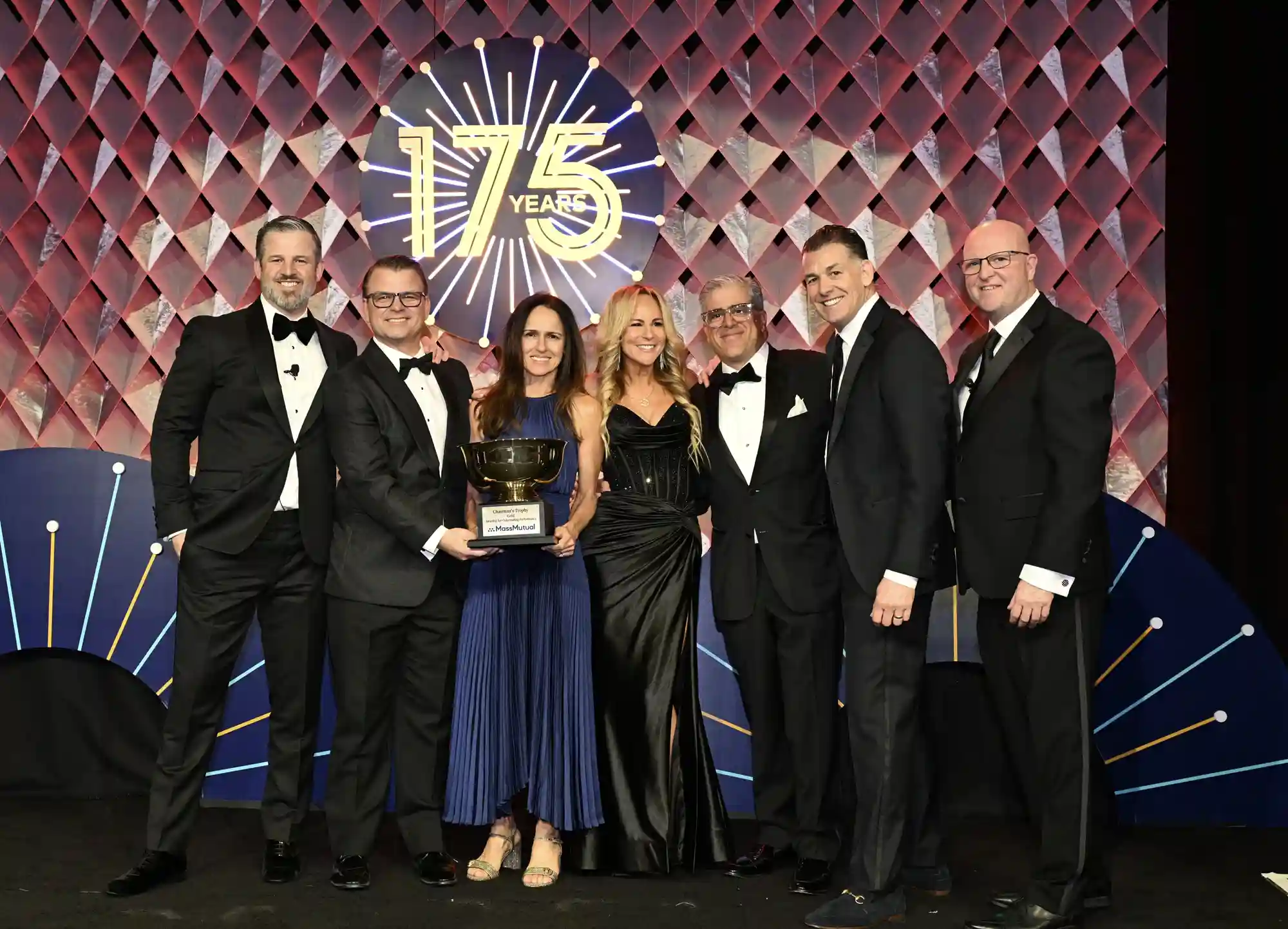 Picture of people dressed in tuxedo's including Stefan Greenberg, Lenox Advisors General Agent, holding the MassMutual Gold Bowl Award
